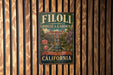 A vintage-style metal sign for Filoli Historic House & Garden in California, featuring a garden scene with a fountain and flowers.