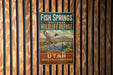 A vintage-style metal sign for Fish Springs National Wildlife Refuge in Utah, featuring an illustration of ducks flying over a scenic landscape.