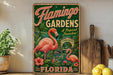 A vintage-style sign for "Flamingo Gardens" in Florida, featuring a pink flamingo and tropical foliage.