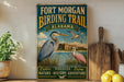 A vintage-style sign for the Fort Morgan Birding Trail in Alabama, featuring illustrations of birds and a scenic landscape.