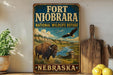 A vintage-style metal sign for the Fort Niobrara National Wildlife Refuge in Nebraska, featuring an illustration of a buffalo and a bird in a scenic landscape.