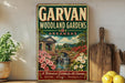 A vintage-style sign for the Garvan Woodland Gardens in Arkansas, featuring a scenic illustration of a garden with a bridge, flowers, and a waterfall.