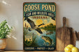 A vintage-style metal sign advertising a "Goose Pond Fish and Wildlife Area Indiana" with a goose in flight, a fish swimming, and a bird perched on a branch. The sign also includes the text "CONSERVE * PROTECT * ENJOY".