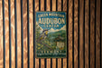 A vintage-style sign for the Green Mountain Audubon Center in Vermont, featuring a bird and a scenic landscape.