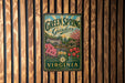 A vintage-style metal sign for "Green Spring Gardens" in Virginia, featuring a garden scene with flowers and a gazebo.