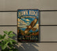A vintage metal sign for Hawk Ridge Bird Observatory in Minnesota, featuring an illustration of a hawk in flight against a scenic background.