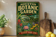 A vintage-style metal sign for the Houston Botanic Garden in Texas, featuring a lush garden scene with various plants and flowers.