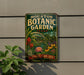 A vintage-style metal sign for the Houston Botanic Garden in Texas, featuring a lush garden scene with various plants and flowers.