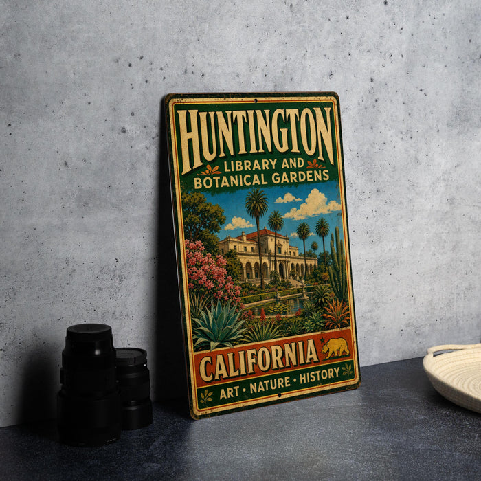 A vintage metal sign for Huntington Library and Botanical Gardens in California, featuring an illustration of a building surrounded by lush greenery and palm trees.