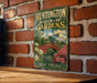 A vintage metal sign for the Huntington Museum of Art Gardens in West Virginia, featuring a garden scene with a red bridge and flowers.