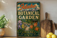 A vintage-style metal sign for the Idaho Botanical Garden, featuring a colorful illustration of flowers and a path leading through a lush garden.