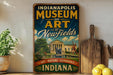 A vintage-style sign for the Indianapolis Museum of Art, featuring an illustration of the museum's exterior and a fountain, with the text "ART - NATURE - EXPERIENCE - INDIANAPOLIS" prominently displayed.