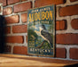 A vintage-style metal sign for John James Audubon State Park in Kentucky, featuring a bird illustration and text.