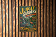 A vintage-style sign for "Jungle Gardens" is displayed on a wooden wall, featuring illustrations of alligators, birds, and tropical plants.