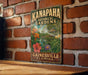 A vintage-style metal sign for Kanapaha Botanical Gardens in Gainesville, Florida, featuring a lush garden scene with colorful flowers and plants.