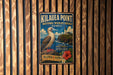 A vintage metal sign for the National Wildlife Refuge in Hawaii, featuring a bird and a lighthouse, is displayed on a wooden wall.