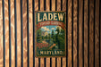 A vintage metal sign for "LADEW TOPIARY GARDENS MARYLAND" is displayed on a wooden wall.