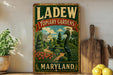 A vintage-style metal sign for "LADEW TOPIARY GARDENS" in Maryland, featuring a large illustration of a peacock in a garden setting.