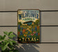 A vintage-style metal sign for the Lady Bird Johnson Wildflower Center in Texas, featuring a colorful illustration of a garden with flowers and a building in the background.