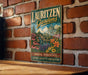A vintage-style metal sign for Lauritzen Gardens in Omaha, Nebraska, featuring a garden scene with flowers and a building.