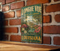A vintage-style metal sign for "LONGUE VUE HOUSE AND GARDENS" in New Orleans, Louisiana, hanging on a brick wall.
