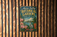 A vintage-style metal sign for "Marie Selby Botanical Gardens" in Florida, featuring a tropical landscape with palm trees, orchids, and a bird.