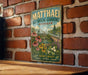 A vintage-style metal sign for the Mathaei Botanical Gardens in Michigan, featuring a garden scene with flowers and a greenhouse.