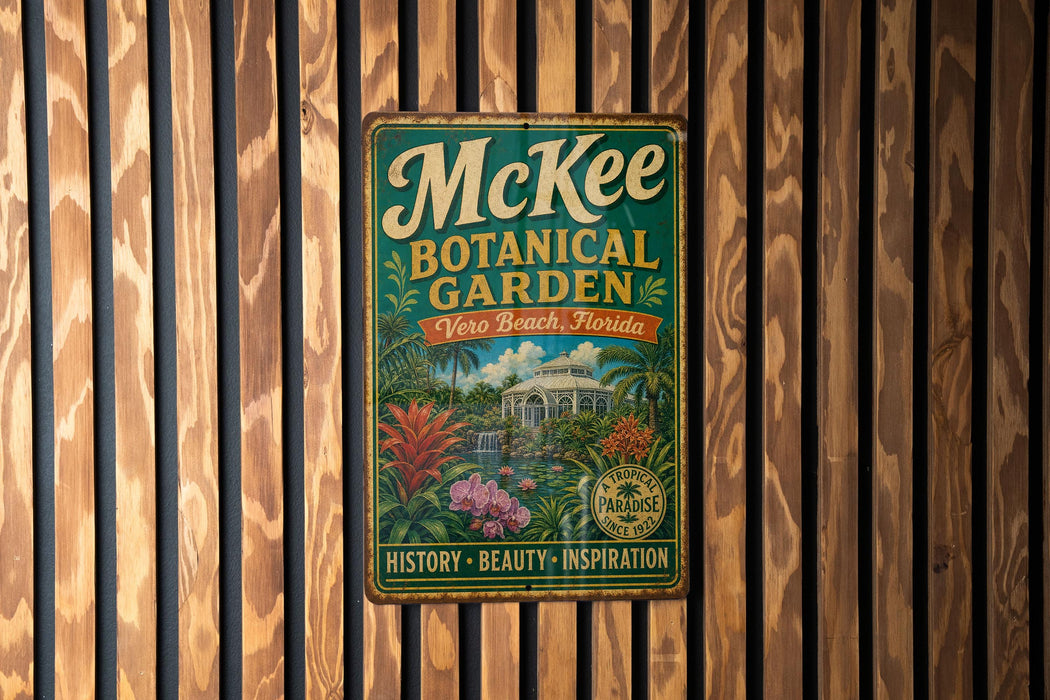 A vintage-style metal sign for the McKee Botanical Garden in Vero Beach, Florida, featuring a tropical garden scene with palm trees, flowers, and a building.