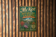 A vintage-style metal sign for the McKee Botanical Garden in Vero Beach, Florida, featuring a tropical garden scene with palm trees, flowers, and a building.