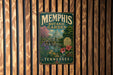 A vintage-style metal sign for the Memphis Botanic Garden in Tennessee, featuring a colorful illustration of the garden's landscape and architecture.