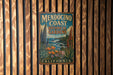 A vintage metal sign for Mendocino Coast Botanical Gardens in California, featuring an illustration of a garden landscape with various plants and flowers.