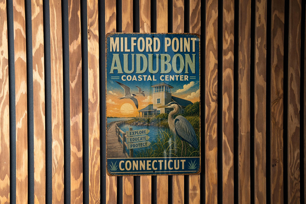 A vintage metal sign for Milford Point Audubon Coastal Center in Connecticut, featuring a seagull and a lighthouse, is displayed on a wooden wall.