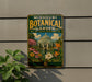 A vintage-style metal sign for the Missouri Botanical Garden, featuring a colorful illustration of the greenhouse and various flowers.