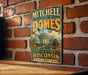 A vintage-style metal sign for Mitchell Park Domes in Milwaukee, Wisconsin, featuring a large illustration of the domed structures and the text "Mitchell Park Domes" prominently displayed.
