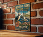 A vintage-style metal sign for the Monhegan Island Bird Sanctuary in Maine, featuring a puffin and a seagull, is displayed on a brick wall.