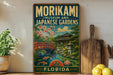 A vintage-style metal sign for the Morikami Museum and Japanese Gardens in Florida, featuring a scenic landscape with a bridge, pond, and cherry blossom trees.