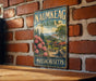 A vintage metal sign for the Naimkeag Garden in Massachusetts, featuring a scenic illustration of a garden with trees, flowers, and a winding path.