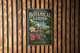 A vintage-style metal sign for the New Orleans Botanical Garden, featuring illustrations of flowers and plants, mounted on a wooden wall.