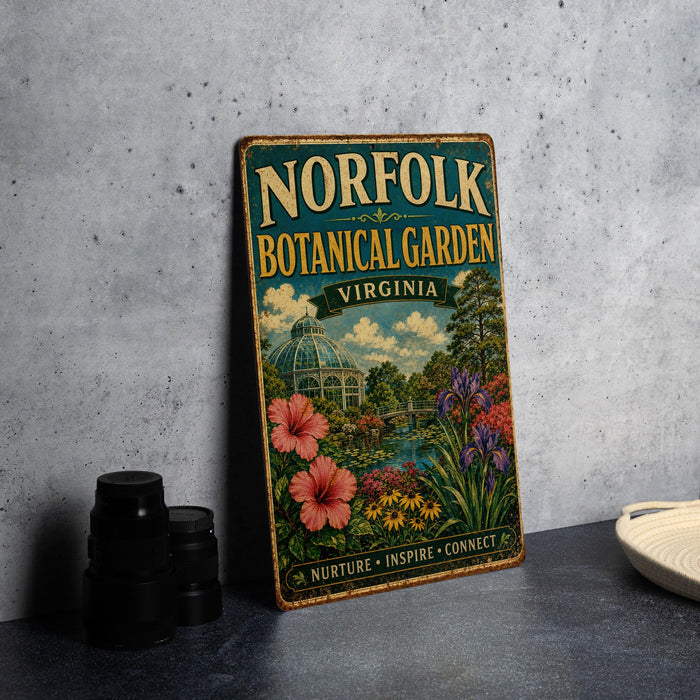 A vintage-style metal sign for the Norfolk Botanical Garden in Virginia, featuring a colorful illustration of a garden with flowers, plants, and a greenhouse.