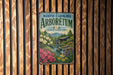 A vintage metal sign for the North Carolina Arboretum, featuring a scenic landscape with a waterfall and flowers.