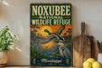 A vintage-style sign for the Noxubee National Wildlife Refuge in Mississippi, featuring an illustration of a bird in flight and a bird on the ground, with a sunset in the background.
