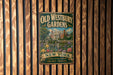 A vintage metal sign for Old Westbury Gardens, featuring a large illustration of a historic building surrounded by a garden, is displayed on a wooden wall.