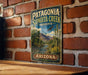 A vintage-style metal sign for Patagonia Sonoita Creek Preserve in Arizona, featuring a desert landscape with a cactus and a river.