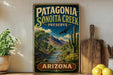 A vintage-style sign for Patagonia Sonoita Creek Preserve in Arizona, featuring a desert landscape with a river, cacti, and mountains.