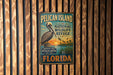 A vintage-style metal sign for the Pelican Island National Wildlife Refuge in Florida, featuring an illustration of a pelican and a sunset landscape.