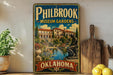 A vintage-style metal sign for Philbrook Museum Gardens in Oklahoma, featuring a painting of a building and a statue, is displayed on a shelf with various kitchen utensils and a potted plant.