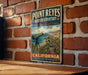 A vintage-style metal sign for Point Reyes Bird Observatory, featuring a telescope and a bird in a natural setting, mounted on a brick wall.