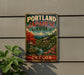 A vintage-style metal sign for the Portland Japanese Garden in Oregon, featuring a scenic landscape with a mountain, pagoda, and cherry blossom trees.