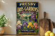 A vintage-style metal sign for Presby Memorial Iris Gardens, featuring a colorful illustration of the gardens and a gazebo.