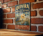 A vintage-style metal sign for the Quivira National Wildlife Refuge in Kansas, featuring an illustration of a bird and ducks in a natural setting.